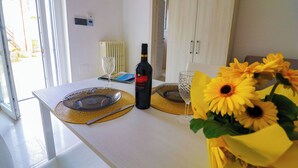 Une table à manger avec une bouteille de vin, un verre et un vase rempli de tournesols.