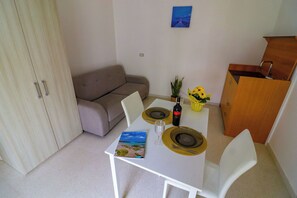 A dining area with a table set for two, a sofa, a small cabinet, and a framed picture on the wall. - Beautiful private villa for 4 people with A/C, WIFI and TV, close to Otranto (Cannole)