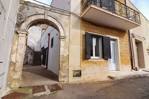 A building with an arched entrance, a balcony with metal railings, and a door with shutters. - Beautiful private villa for 4 people with A/C, WIFI and TV, close to Otranto (Cannole)