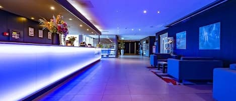 Un vestíbulo de hotel con mostrador de recepción, zona de estar y vistas al interior.