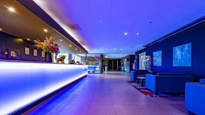 Un vestíbulo de hotel con mostrador de recepción, zona de estar y vistas al interior.