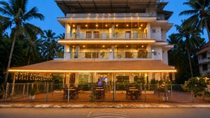 Ein mehrstöckiges Hotel mit Außenbestuhlung und einer überdachten Terrasse.