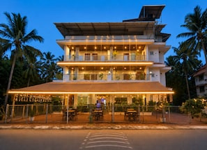 Een meerlaags hotel met buiten zitplaatsen en een overdekt terras.