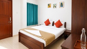 Ein Hotelzimmer mit einem hölzernen Bett, türkisfarbenen Vorhängen, einem Holzschrank und einem Nachttisch mit Flasche und Glas.