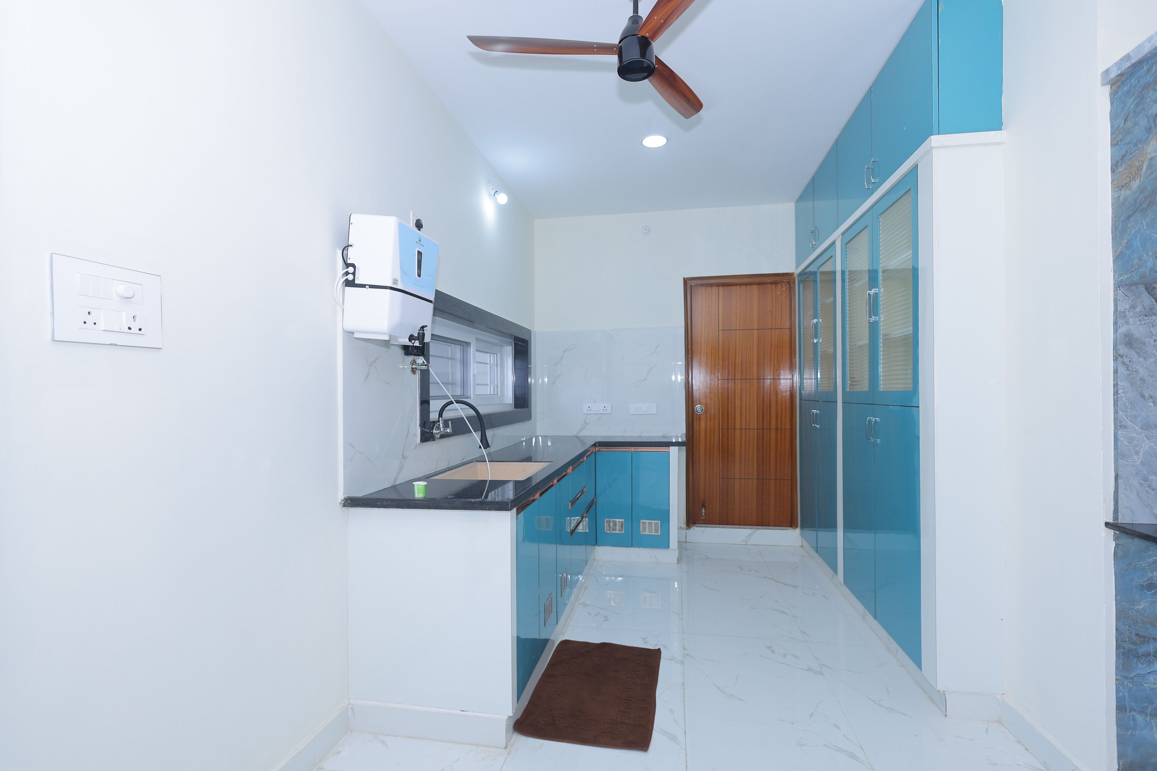 Una cocina con ventilador de techo, horno empotrado y puerta de madera.