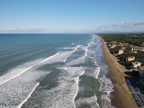 An aerial view of a beach with waves, a row of houses, and a clear sky. - Le Dimore di Santa Costanza by Interhome (San Vincenzo)