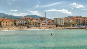 Eine Küstenstadt mit Gebäuden am Strand, bewölktem Himmel und ruhiger See.