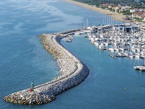 A marina with boats docked, a rocky breakwater, and a statue on a small island. - Le Dimore di Santa Costanza by Interhome (San Vincenzo)
