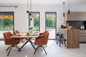 Ein moderner Essbereich mit Holztisch, vier Stühlen und Blick durch große Fenster.