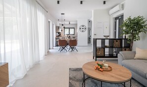 Ein modernes Wohnzimmer mit Sofa, Couchtisch mit Blumen und Essbereich mit Stühlen und Tisch.