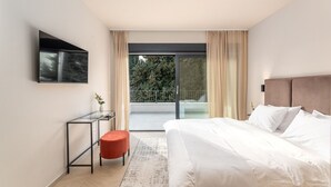 Une chambre moderne avec un grand lit, un bureau et une porte-fenêtre coulissante donnant sur un balcon.