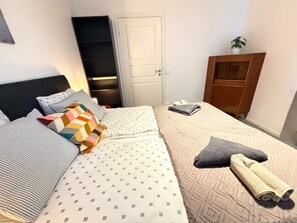 Un dormitorio pequeño y ordenado con cama, almohadas, mesita de noche, armario y una puerta.