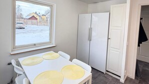 Una cocina compacta con una mesa blanca, sillas y un refrigerador.