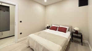 Un dormitorio con cama, mesitas de noche, armario y un respiradero en el techo.