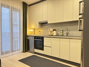 A modern kitchen with a dishwasher, oven, coffee maker, and a small sink. - Newly Built 2BR Residence in Central Şişli (Istanbul)