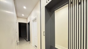Un pasillo con una puerta, una rejilla de ventilación e una lámpara.
