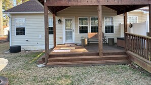 A covered porch with a wooden railing, a bench, and a small table.