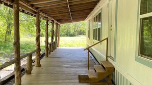 A covered wooden deck with a bench, wooden posts, and a view of a green landscape. - Charming 3-bedroom 2 Bath farmhouse on 7.4 Acres (Trenton)