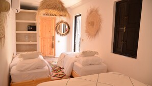 Ein Schlafzimmer mit zwei Betten, einem Holzschrank, einem Spiegel und einer Tür.