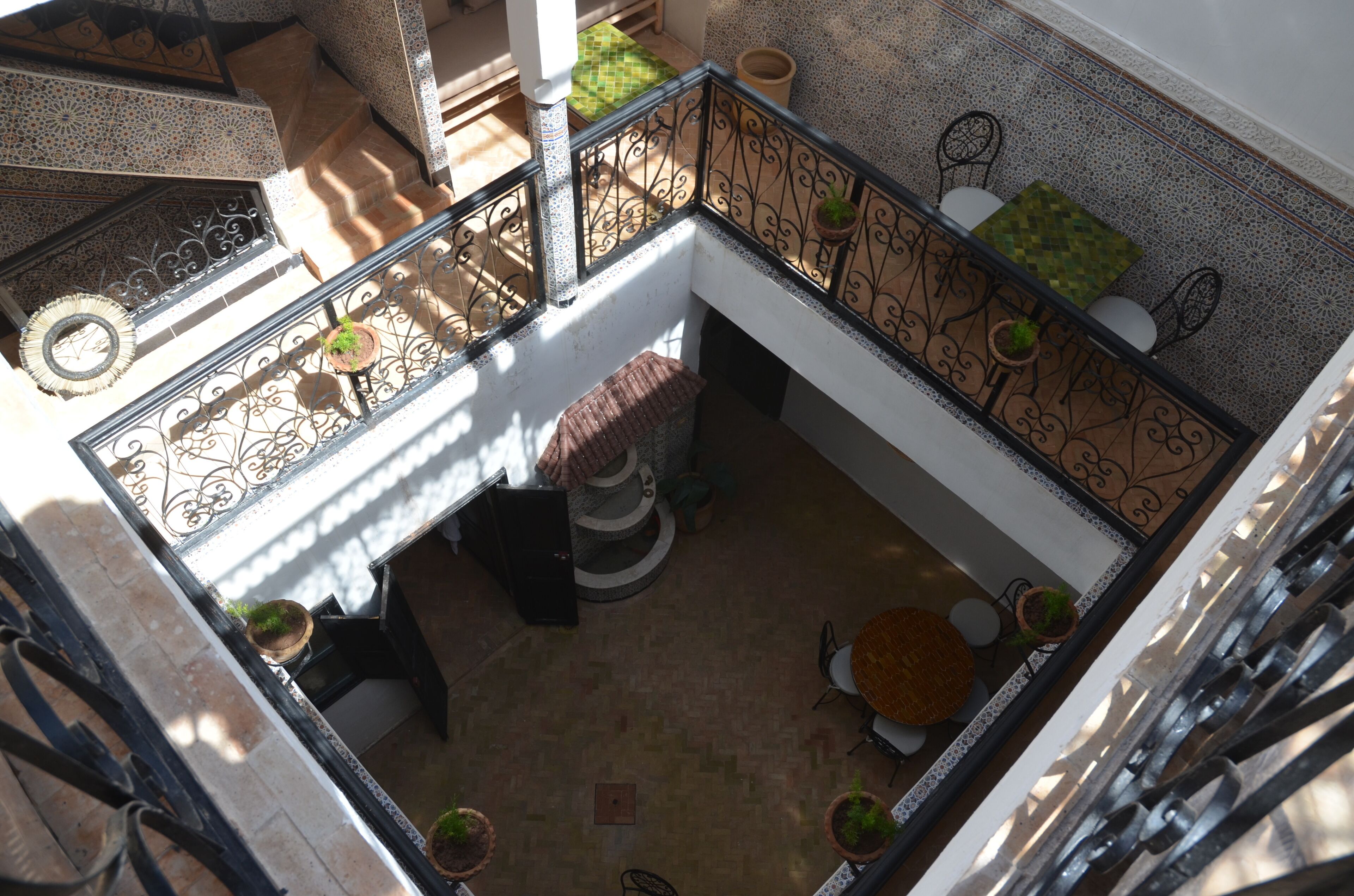 A multi-level interior with a spiral staircase, potted plants, and a tiled floor.