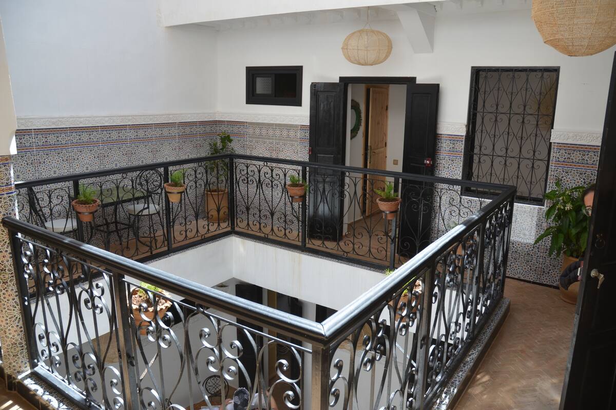 A balcony with wrought iron railings, potted plants, and a tiled floor.