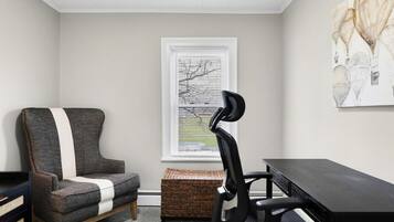 Una habitación con escritorio, silla de oficina, otra silla y una ventana con persianas.