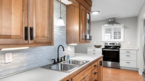 A kitchen with wooden cabinets, stainless steel appliances, and a white countertop. - Country Fields, Wine Country, Pool and More (Auburn)