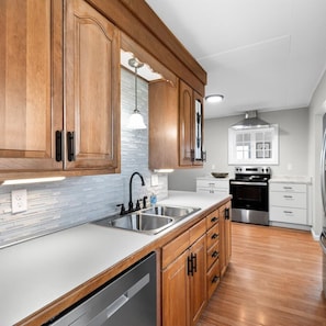 A kitchen with wooden cabinets, stainless steel appliances, and a white countertop. - Country Fields, Wine Country, Pool and More (Auburn)