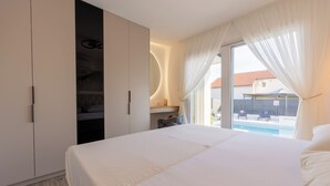 Un dormitorio con cama, armario, espejo y vistas a una piscina.