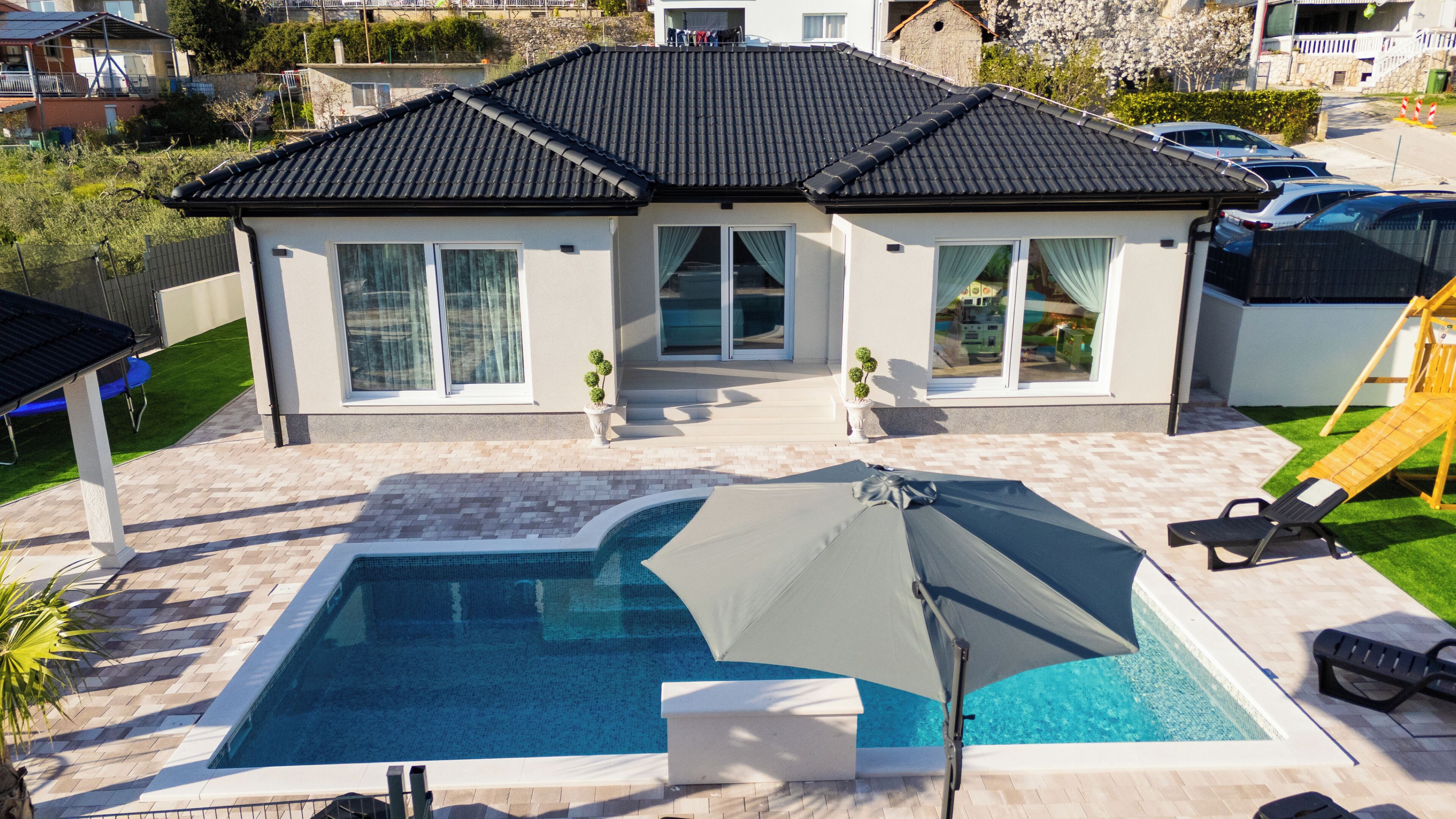 A residential property with a swimming pool, a covered patio, and a play area.