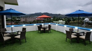 Una terrazza sul tetto con erba sintetica, mobili da esterno e ombrelloni.