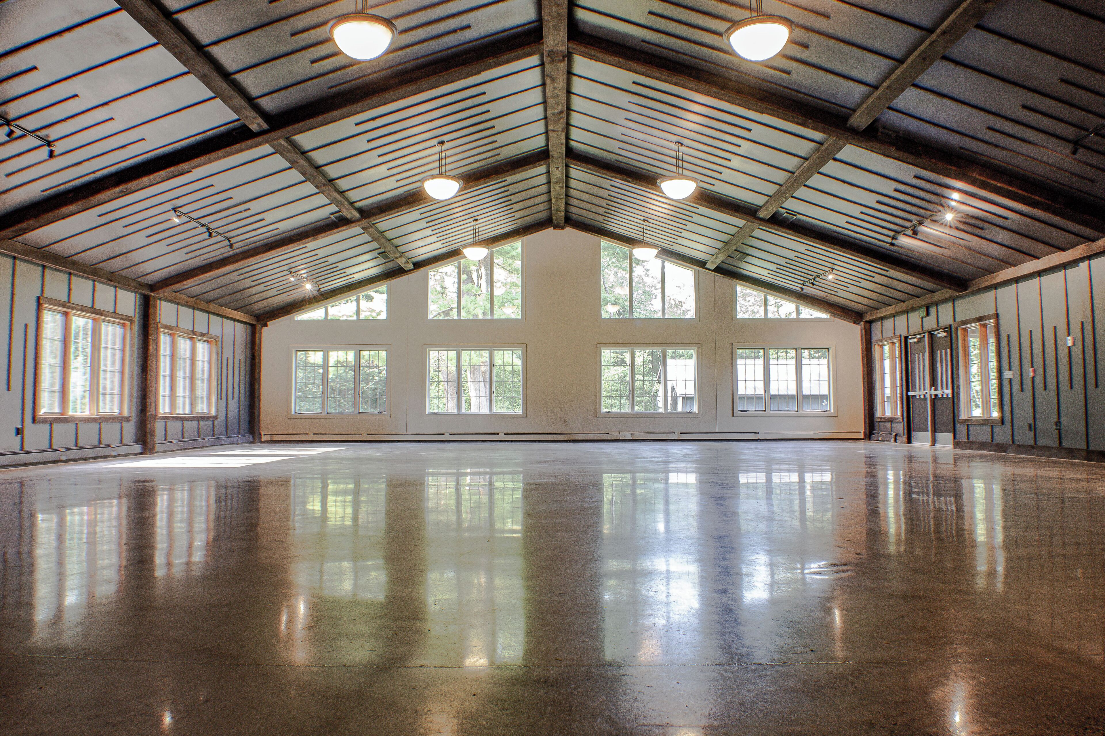 A spacious indoor area with a high ceiling, large windows, and a polished floor.