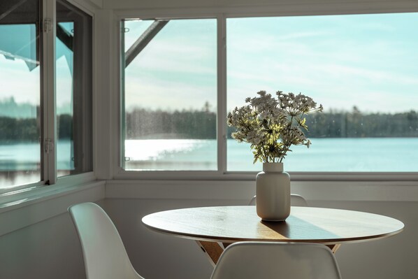 A room with a round table, a white chair, and a vase with flowers. - Vanderkamp (Cleveland)