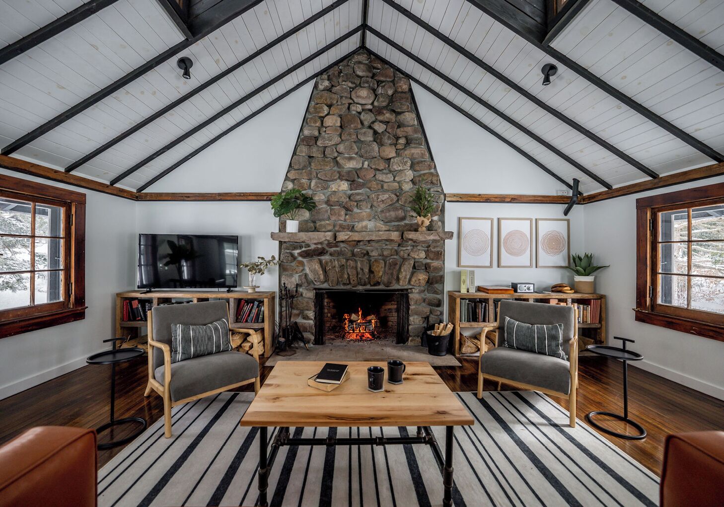 Ein gemütliches Wohnzimmer mit einem Kamin aus Stein, Holzmöbeln und einem Fernseher.