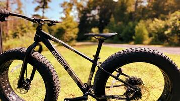 Een mountainbike met een zichtbaar merk op het frame, staand op gras met bomen op de achtergrond.