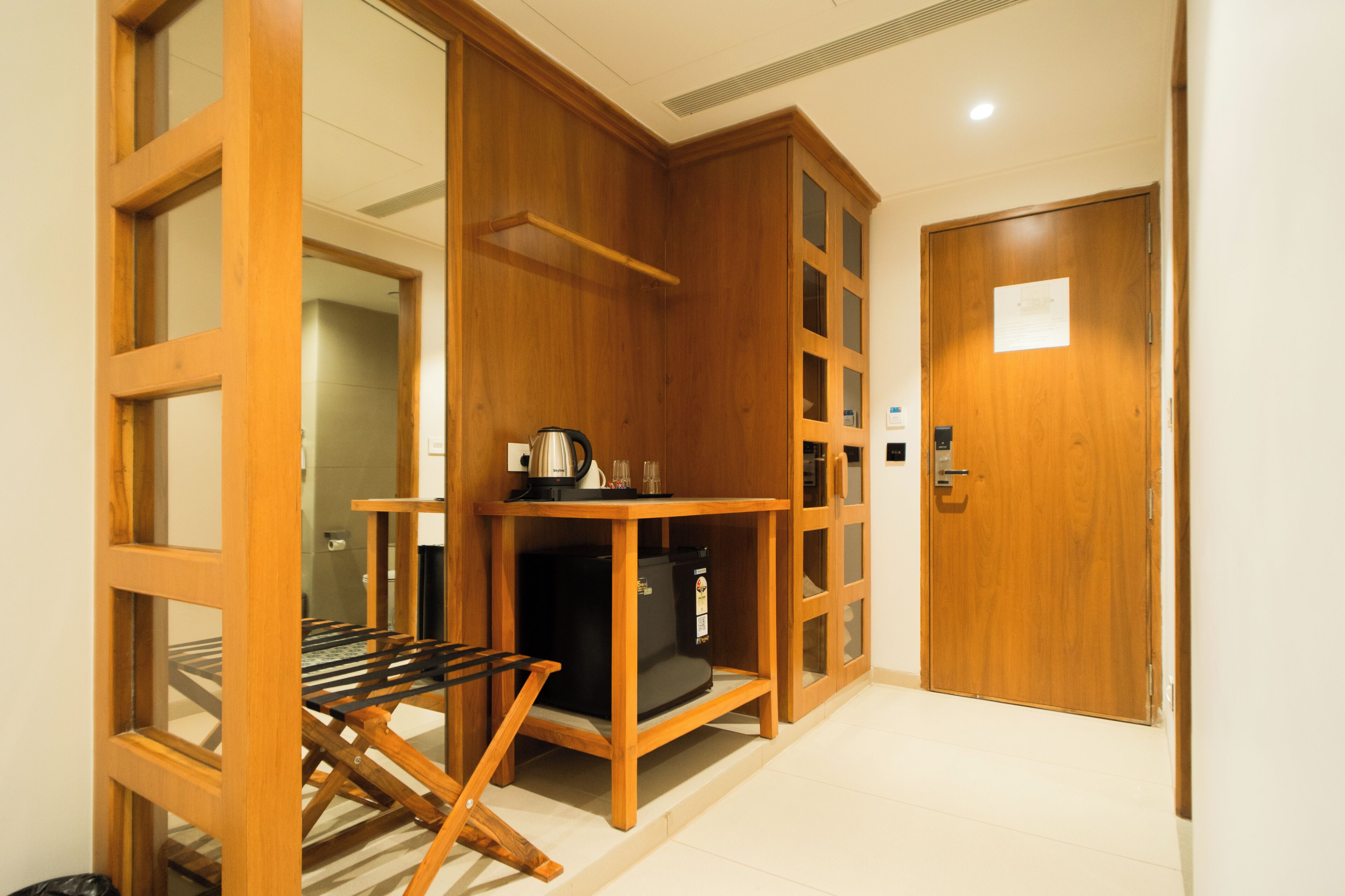 A room with a wooden cabinet, a small table with a kettle, and a door with a sign.