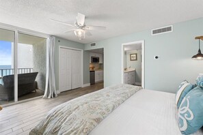 A bedroom with a bed, a ceiling fan, a view to the outside, and a kitchenette in the background. - Luxury 3BR Beachfront Condo Sleeps 8 Gulf Views (Panama City Beach)