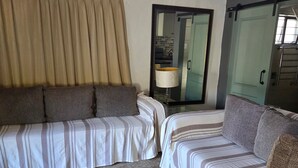 Une chambre avec deux lits, un grand miroir, une lampe et une vue sur la salle de bain.