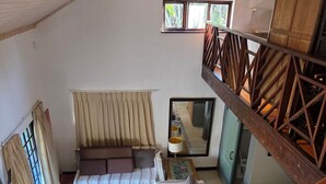 Une pièce comprenant un lit, un canapé, une fenêtre, un miroir et un escalier.