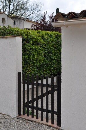 A gated entrance with a white wall and a black metal fence. - House with private garden (VALBONNE)