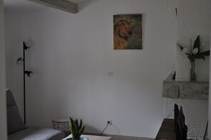 A room with a bed, a small table, a plant, a painting, and a lamp. - House with private garden (VALBONNE)