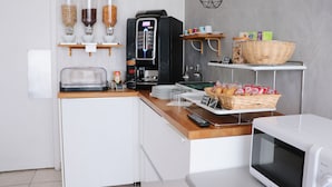A modern kitchen with a coffee machine, a microwave, and a bread basket.