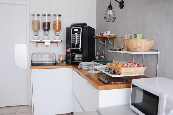 A modern kitchen with a coffee machine, a microwave, and a bread basket.