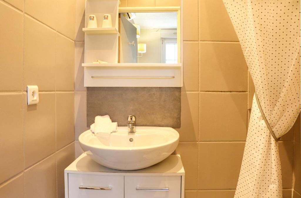 A bathroom with a white sink, a mirror above it, and a towel on the counter.
