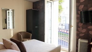 A bedroom with a bed, a chair, a wardrobe, a radiator, and a TV.