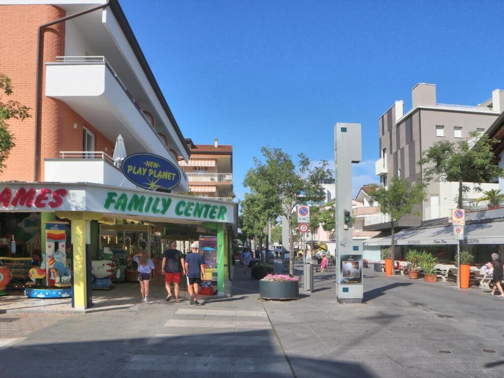 A family center with a play area, a sign for a new play planet, and a building with a balcony.