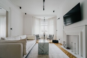 A modern living room with a sofa, a marble coffee table, a fireplace, and a television mounted on the wall. - Designer apartment overlooking Freedom Square, Novi Sad (Novi Sad)