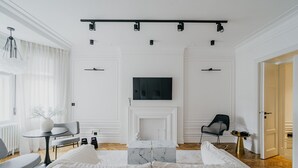 Moderni olohuone, jossa on sohva, sohvapöytä, takka ja sen yläpuolelle asennettu televisio.