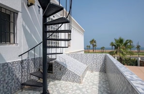 Een modern gebouw met een spiltrap, betegelde vloer en uitzicht op het strand.