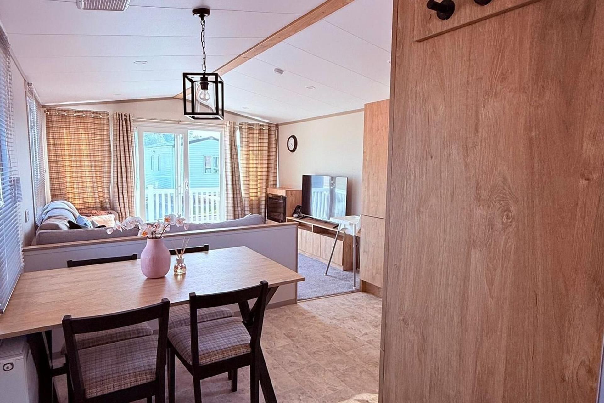 A living room with a wooden dining table, chairs, a TV, and a sofa.